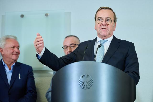 03 December 2025, Berlin: Boris Pistorius (R), German Minister of Defense speaks at the press statement in the Federal Ministry of Defense, while Armin Papperger (l), CEO, Rheinmetall and Carsten Breuer (concealed), Inspector General of the Bundeswehr stand behind him. Pistorius receives representatives of companies involved in the digitization of land-based operations (D-LBO): The armaments project aims to digitize communication for combat. Photo: Annette Riedl/dpa