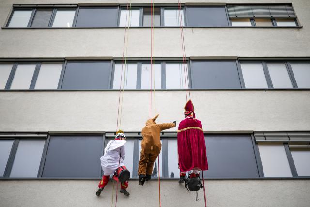 03 December 2025, North Rhine-Westphalia, Duisburg: Height rescuers, dressed as Santa Claus, angels and reindeer, abseil down from a building at the Duisburg Heart Center, where they are delivering presents to young patients at the Children's Heart Center in Duisburg. Photo: Christoph Reichwein/dpa