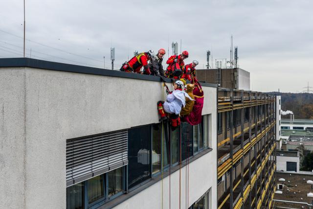 03 December 2025, North Rhine-Westphalia, Duisburg: Height rescuers, dressed as Santa Claus, angels and reindeer, abseil down from a building at the Duisburg Heart Center, where they are delivering presents to young patients at the Children's Heart Center in Duisburg. Photo: Christoph Reichwein/dpa