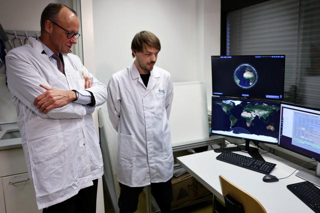 03 December 2025, Berlin: German Chancellor Friedrich Merz (L) looks at a satellite system during his visit to Berlin Space Technologies (BST) in Adlershof. Photo: Nadja Wohlleben/Reuters/Pool/dpa