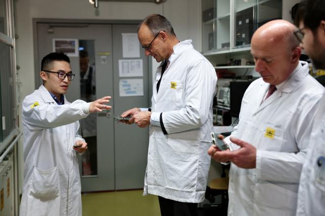 03 December 2025, Berlin: German Chancellor Friedrich Merz (C) talks to an engineer during his during his visit to Berlin Space Technologies (BST) in Adlershof. Photo: Nadja Wohlleben/Reuters/Pool/dpa