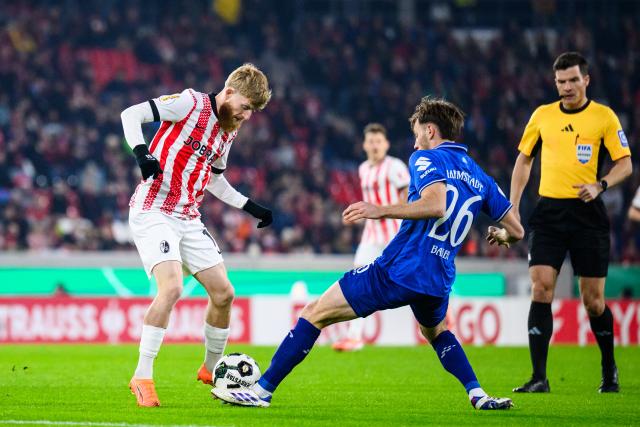 03 December 2025, Baden-Württemberg, Freiburg im Breisgau: Freiburg's Jan-Niklas Beste (L) and Darmstadt's Matthias Bader battle for the ball during the German DFB Cup round of 16 soccer match between SC Freiburg and Darmstadt 98 at Europa-Park Stadium. Photo: Tom Weller/dpa - IMPORTANT NOTICE: DFL and DFB regulations prohibit any use of photographs as image sequences and/or quasi-video.