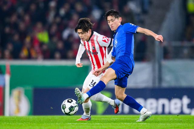 03 December 2025, Baden-Württemberg, Freiburg im Breisgau: Freiburg's Yuito Suzuki and Darmstadt's Hiroki Akiyama (R) battle for the ball during the German DFB Cup round of 16 soccer match between SC Freiburg and Darmstadt 98 at Europa-Park Stadium. Photo: Tom Weller/dpa - IMPORTANT NOTICE: DFL and DFB regulations prohibit any use of photographs as image sequences and/or quasi-video.