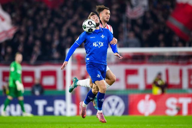 03 December 2025, Baden-Württemberg, Freiburg im Breisgau: Darmstadt's Killian Corredor and Freiburg's Max Rosenfelder battle for the ball during the German DFB Cup round of 16 soccer match between SC Freiburg and Darmstadt 98 at Europa-Park Stadium. Photo: Tom Weller/dpa - IMPORTANT NOTICE: DFL and DFB regulations prohibit any use of photographs as image sequences and/or quasi-video.