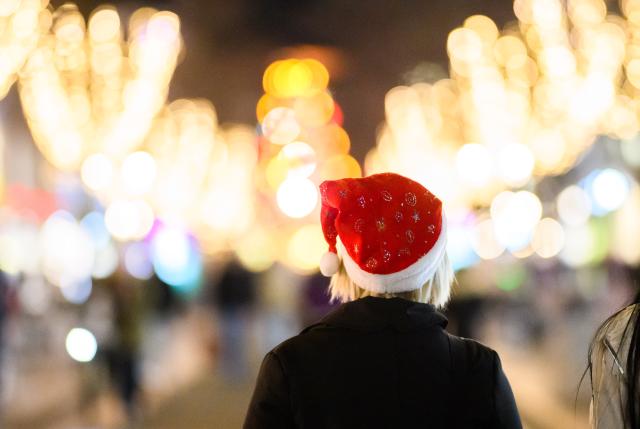 03 December 2025, Lower Saxony, Hanover: A woman wearing a Santa hat walks through the city center at the Christmas market in Hanover. German Christmas markets are massively arming themselves after attacks in previous years. Photo: Julian Stratenschulte/dpa