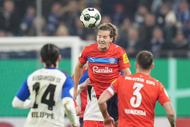 03 December 2025, Hamburg: Holstein Kiel's John Tolkin (C) in action during the German DFB Cup round of 16 soccer match between Hamburger SV and Holstein Kiel at the Volksparkstadion. Photo: Marcus Brandt/dpa - WICHTIGER HINWEIS: Gemäß den Vorgaben der DFL Deutsche Fußball Liga bzw. des DFB Deutscher Fußball-Bund ist es untersagt, in dem Stadion und/oder vom Spiel angefertigte Fotoaufnahmen in Form von Sequenzbildern und/oder videoähnlichen Fotostrecken zu verwerten bzw. verwerten zu lassen.