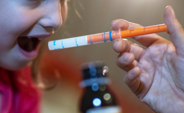 FILED - 13 September 2023, Saxony, Leipzig: A mother administers a dose of fever syrup to her daughter. Photo: Hendrik Schmidt/dpa