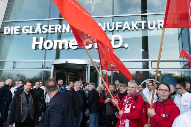 04 December 2025, Saxony, Dresden: Participants in a rally organized by IG Metall Dresden stand on the terrace of Volkswagen's Transparent Factory after a works meeting. Production of the ID.3 electric model at the Transparent Factory, which employs around 320 people, is scheduled to end at the end of the year. Photo: Sebastian Kahnert/dpa