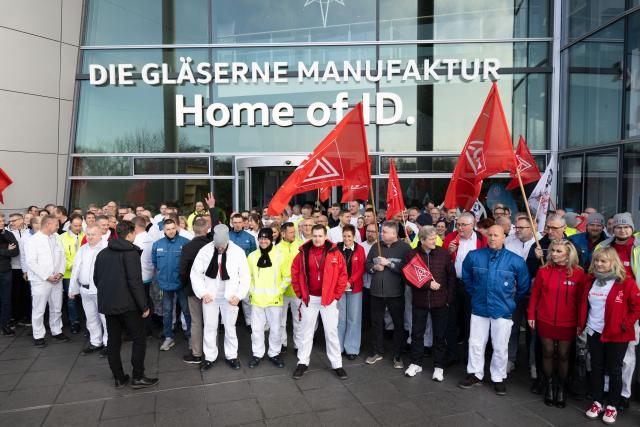 04 December 2025, Saxony, Dresden: Participants in a rally organized by IG Metall Dresden stand on the terrace of Volkswagen's Transparent Factory after the works meeting. Production of the ID.3 electric model at the site, which employs around 320 people, is slated to end at the close of the year. Photo: Sebastian Kahnert/dpa