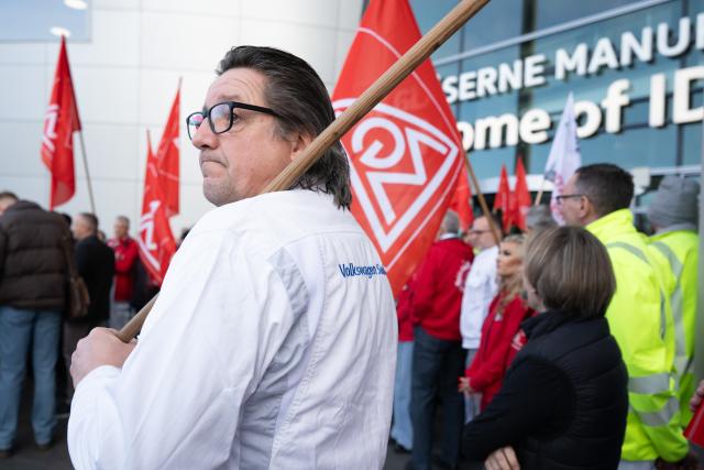 04 December 2025, Saxony, Dresden: Participants in a rally organized by IG Metall Dresden stand on the terrace of Volkswagen's Transparent Factory after a works meeting. Production of the ID.3 electric model at the site, which employs around 320 people, is scheduled to end at the close of the year. Photo: Sebastian Kahnert/dpa