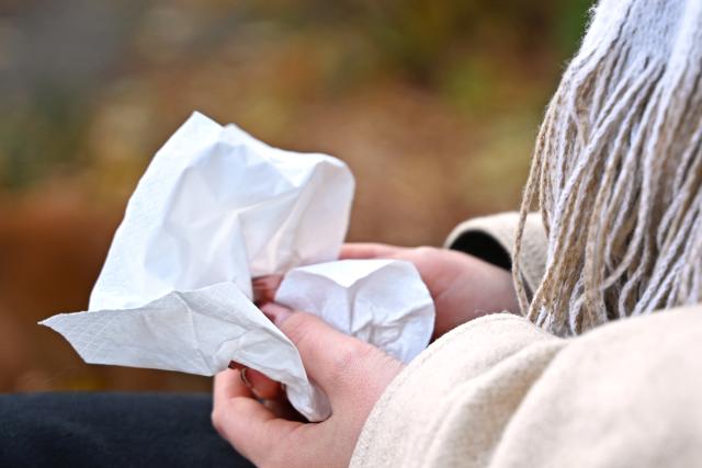 SYMBOL - 24 October 2025, Berlin: A woman holds a handkerchief as she sits on a park bench. Photo: Elisa Schu/dpa