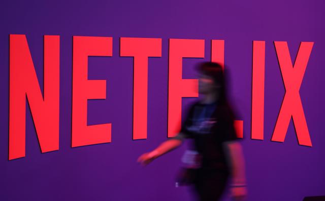 FILED - 20 August 2025, North Rhine-Westphalia, Cologne: A woman walks past the Netflix stand. Netflix is reportedly leading the race to acquire Hollywood heavyweight Warner Bros Discovery (WBD), multiple US media outlets reported late on Thursday. Photo: Oliver Berg/dpa