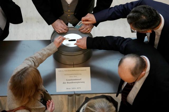05 December 2025, Berlin: Germany's Chancellor Friedrich Merz (R) casts his voting card in the German Bundestag during a roll-call vote on the law for a new military service. Photo: Kay Nietfeld/dpa
