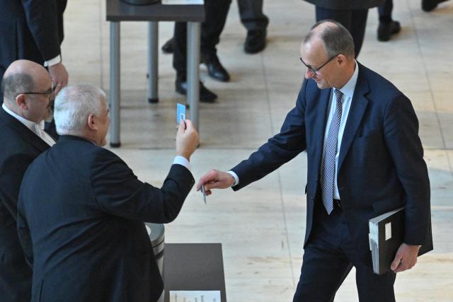 05 December 2025, Berlin: Germany's Chancellor Friedrich Merz (R) casts his voting card in the German Bundestag during a roll-call vote on the law for a new military service. Photo: Christophe Gateau/dpa
