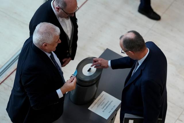 05 December 2025, Berlin: Germany's Chancellor Friedrich Merz (R) casts his voting card in the German Bundestag during a roll-call vote on the law for a new military service. Photo: Kay Nietfeld/dpa