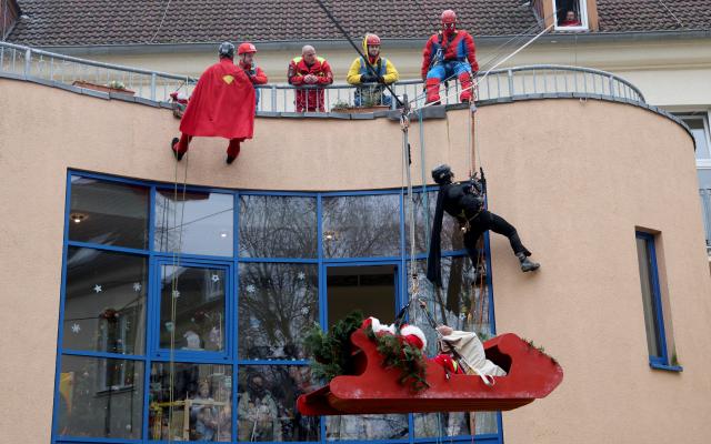 05 December 2025, Mecklenburg-Western Pomerania, Rostock: Santa Claus in a flying sleigh and other superheroes bring presents to the patients in the children's and youth clinic at the university hospital. Photo: Bernd Wüstneck/dpa