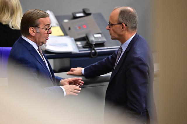 05 December 2025, Berlin: Boris Pistorius (L), Germany's of Defence Minister, and Germany's Chancellor Friedrich Merz speak on the sidelines of the German Bundestag session. Photo: Christophe Gateau/dpa
