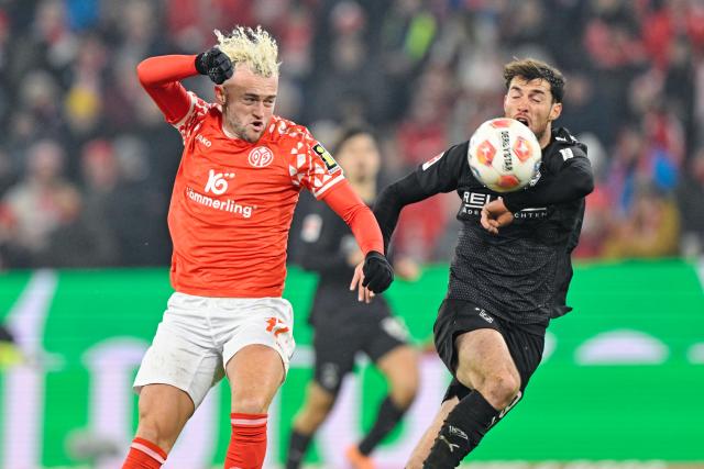 05 December 2025, Rhineland-Palatinate, Mainz: Mainz Benedict Hollerbach (L) and Gladbach's Joe Scally battle for the ball during the German Bundesliga soccer match between FSV Mainz 05 and Borussia Moenchengladbach at Mewa Arena. Photo: Uwe Anspach/dpa - IMPORTANT NOTICE: DFL and DFB regulations prohibit any use of photographs as image sequences and/or quasi-video.