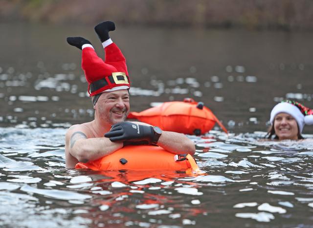 06 December 2025, Lower Saxony, Goslar: A participant wearing a funny hat takes part in the traditional St. Nicholas swim that happens in the three-degree water of the Herzberg pond at an air temperature of just under four degrees. Photo: Matthias Bein/dpa