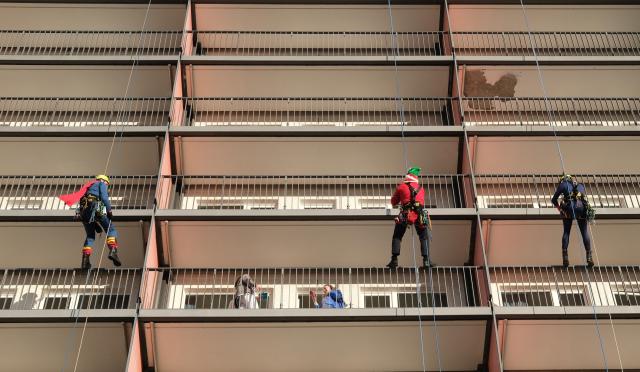 06 December 2025, Saxony, Chemnitz: Memebers of the Chemnitz fire department's height rescue team abseil down the facade of the hospital in Christmas costumes. For the past five years, fire department rescuers have been organizing an abseiling campaign at children's hospitals across Germany on St. Nicholas' Day and delighting patients and staff with small gifts. Photo: Sebastian Willnow/dpa