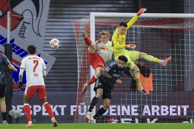 06 December 2025, Saxony, Leipzig: Leipzig's Conrad Harder and Eintracht Frankfurt's Nnamdi Collins and goalkeeper Michael Zetterer battle for the ball during the German Bundesliga soccer match between RB Leipzig and Eintracht Frankfurt at the Red Bull Arena. Photo: Jan Woitas/dpa - IMPORTANT NOTICE: DFL and DFB regulations prohibit any use of photographs as image sequences and/or quasi-video.