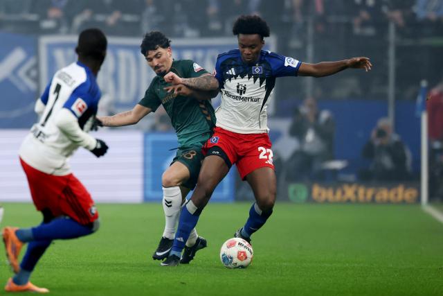 07 December 2025, Hamburg: Werder Bremen's Cameron Puertas (C) and Hamburger's Aboubaka Soumahoro (R) battle for the ball during the German Bundesliga soccer match between Hamburger SV and SV Werder Bremen at the Volksparkstadion. Photo: Christian Charisius/dpa - IMPORTANT NOTICE: DFL and DFB regulations prohibit any use of photographs as image sequences and/or quasi-video.