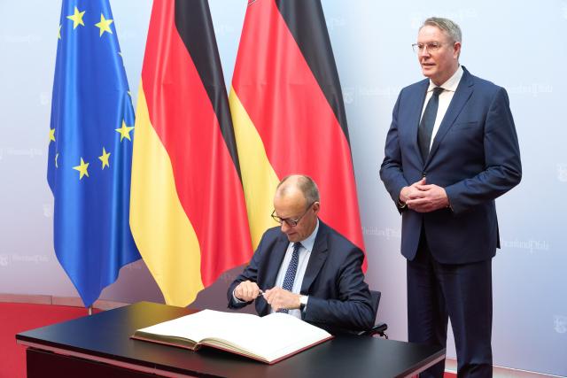 09 December 2025, Rhineland-Palatinate, Mainz: German Chancellor Friedrich Merz signs the Golden Book of the State Government in the State Chancellery, next to him stands Alexander Schweitzer, Minister President of Rhineland-Palatinate. The focus of the Chancellor's visit is a political exchange and a joint meeting of the Rhineland-Palatinate cabinet with the Federal Chancellor. Photo: Thomas Frey/dpa