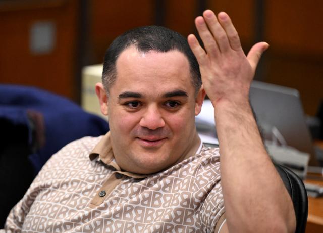 09 December 2025, Hesse, Frankfurt/Main: One of the three defendants, Ukrainian Robert A. (C), gestures as he waits in the courtroom on the opening day of the trial of three men accused of spying for Russia. Three men are said to have had a man in their sights for a Russian secret service. A crucial meeting is said to have been planned in a café in Frankfurt. Now the trial begins. Photo: -/POOL/AFP/dpa