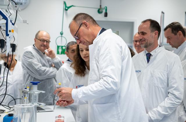 12 September 2025, Rhineland-Palatinate, Mainz: Germany Chancellor Friedrich Merz conducts a pipetting campaign under the guidance of Iris Lade (TRON GmbH). TRON gGmbH is one of the leading biomedical research institutes in Germany. Chancellor Merz makes his inaugural visit to Rhineland-Palatinate. Photo: Harald Tittel/dpa