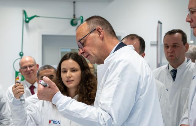 12 September 2025, Rhineland-Palatinate, Mainz: Iris Lade (L) from the company TRON shows Chancellor Friedrich Merz a pipetting action in the in-house laboratory. TRON gGmbH is one of the leading biomedical research institutes in Germany. Chancellor Merz is on his inaugural visit to Rhineland-Palatinate. Photo: Harald Tittel/dpa