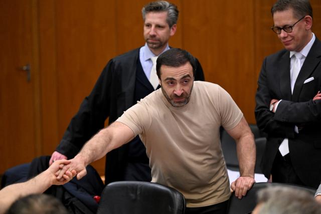 09 December 2025, Hesse, Frankfurt/Main: Armenian defendant Vardges I. (C), waits next to his lawyer Tobias Groscurth (L) in the courtroom on the opening day of the trial against three men for spying for Russia. Three men are said to have had a man in their sights for a Russian secret service. A crucial meeting is said to have been planned in a cafe in Frankfurt. Now the trial begins. Photo: -/POOL/AFP/dpa