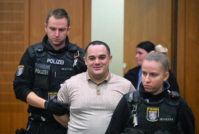 09 December 2025, Hesse, Frankfurt/Main: Ukrainian defendant Robert A. (C), is led into the courtroom on the opening day of the trial against three men for spying for Russia. Three men are said to have had a man in their sights for a Russian secret service. A crucial meeting is said to have been planned in a cafe in Frankfurt. Now the trial begins. Photo: -/POOL/AFP/dpa