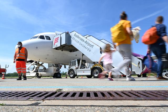 FILED - 17 June 2021, Baden-Wuerttemberg, Friedrichshafen: Passengers walk with luggage to the plane to Skopje in northern Macedonia at Lake Constance Airport. Photo: Felix Kästle/dpa