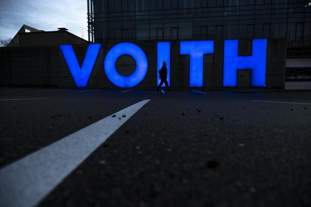 FILED - 08 December 2025, Baden-Württemberg, Heidenheim: The silhouette of a man can be seen in front of the company logo at Voith's headquarters. Photo: Stefan Puchner/dpa