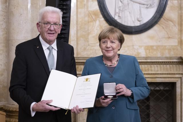 09 December 2025, Baden-Wuerttemberg, Stuttgart: Minister President of Baden-Wuerttemberg Winfried Kretschmann (L) presents former Federal Chancellor Angela Merkel with the Staufer Medal in Gold for her coronavirus policy in the New Palace. Photo: Marijan Murat/dpa