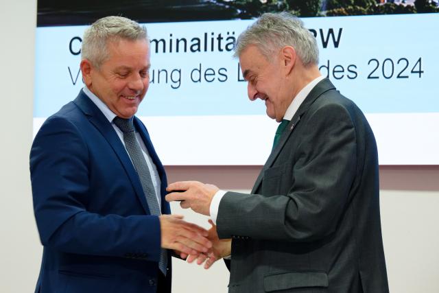 10 December 2025, North Rhine-Westphalia, Duesseldorf: Achim Schmitz (L), Chief Criminal Director and Head of Department 1 at the State Criminal Police Office of North Rhine-Westphalia (L), receives a small gift from Herbert Reul, Minister of the Interior of North Rhine-Westphalia (R), after a press conference to present the 2024 Clan Crime Situation Report. Photo: Henning Kaiser/dpa