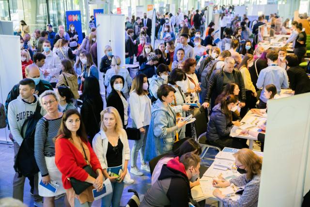 FILED - 02 June 2022, Berlin: Ukrainian refugees stand in front of information booths during a job fair organized by the Berlin Chamber of Industry and Commerce and the Employment Agency. Photo: Christoph Soeder/dpa