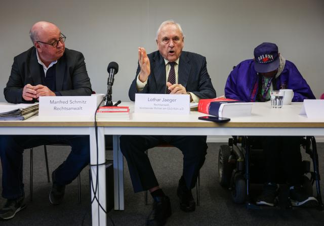 11 December 2025, North Rhine-Westphalia, Cologne: Lothar Jaeger (C), lawyer and former judge, speaks alongside "Hardy" (R) from Cologne and lawyer Manfred Schmitz (L) during a press conference on a one-million-euro compensation claim against the Catholic Church. "Hardy" says he was tortured and brutally abused by priests in the Archdiocese of Cologne. Photo: Oliver Berg/dpa
