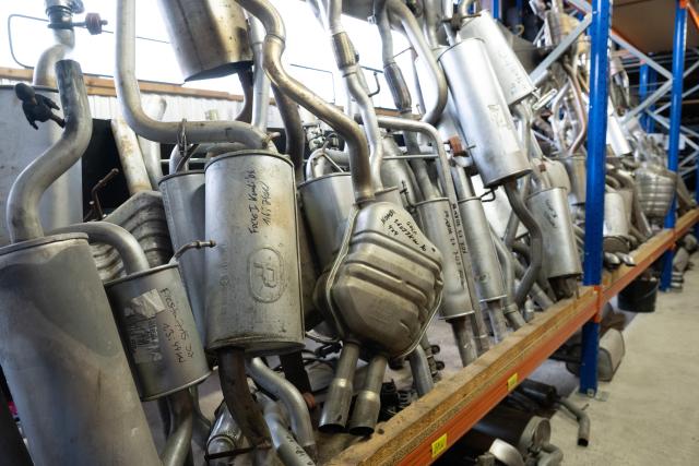 FILED - 07 October 2025, Saxony, Dresden: Exhaust pipes from various vehicles in a car recycling warehouse. Car recycling companies dismantle and recycle vehicle parts for reuse or disposal. Photo: Sebastian Kahnert/dpa