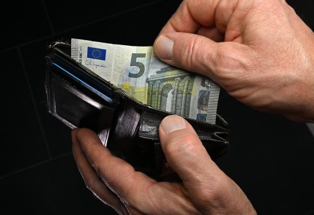 FILED - 12 November 2025, Thuringia, Erfurt: A man opens his wallet and pulls out a five-euro bill. The number of insolvencies in Germany is still high compared to last year, with 5.7% more in November this year than a year ago, according to official figures released on Friday. Photo: Martin Schutt/dpa