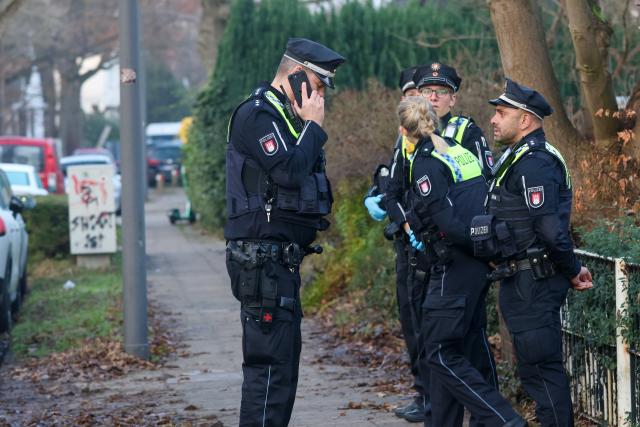 12 December 2025, Hamburg: Police officers stand in front of a house where a shot is said to have been fired while assisting a bailiff. Photo: Bodo Marks/dpa