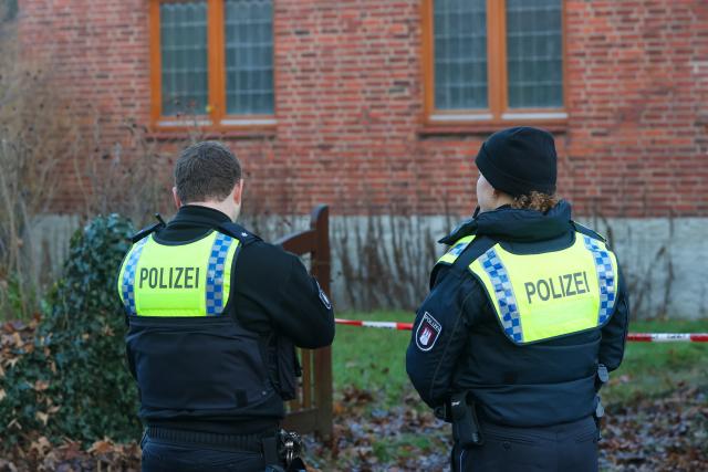12 December 2025, Hamburg: Police officers stand in front of a house where a shot is said to have been fired while assisting a bailiff. Photo: Bodo Marks/dpa
