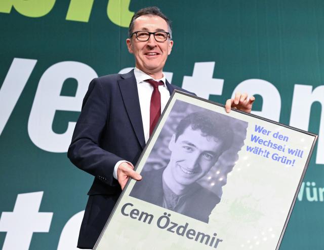 12 December 2025, Baden-Wuerttemberg, Ludwigsburg: Cem Oezdemir, Alliance 90/The Greens (Bündnis 90/Die Grünen) lead candidate for the 2026 state election in Baden-Wuerttemberg, is presented with an election poster from 1994 at the start of the state party conference. Photo: Bernd Weißbrod/dpa