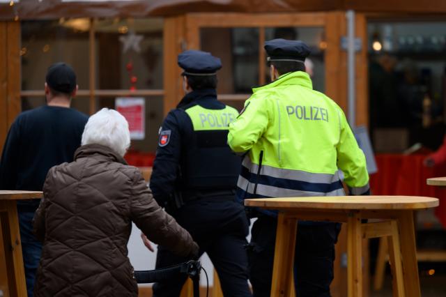 13 December 2025, Lower Saxony, Duderstadt: Police officers walk through the Christmas market. Following the evacuation of the Christmas market on 12.12.2025 in Duderstadt in southern Lower Saxony, the police are still looking for a suspect. Several witnesses claimed to have seen a man with a long gun on Friday evening. Photo: Swen Pförtner/dpa