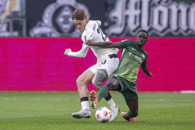 13 December 2025, North Rhine-Westphalia, Moenchengladbach: Moenchengladbach's Luca Netz (L) and Wolfsburg's Sael Kumbedi battle for the ball during the German Bundesliga soccer match between Borussia Moenchengladbach and VfL Wolfsburg at Stadion im Borussia-Park. Photo: David Inderlied/dpa - WICHTIGER HINWEIS: Gemäß den Vorgaben der DFL Deutsche Fußball Liga bzw. des DFB Deutscher Fußball-Bund ist es untersagt, in dem Stadion und/oder vom Spiel angefertigte Fotoaufnahmen in Form von Sequenzbildern und/oder videoähnlichen Fotostrecken zu verwerten bzw. verwerten zu lassen.
