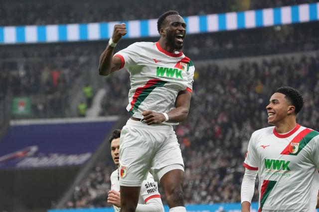 13 December 2025, Hesse, Frankfurt/M.: Augsburg's Chrislain Matsima (L) celebrates a goal, which was disallowed according to VAR during the German Bundesliga soccer match between Eintracht Frankfurt and FC Augsburg at Deutsche Bank Park. Photo: Marc Schüler/dpa - WICHTIGER HINWEIS: Gemäß den Vorgaben der DFL Deutsche Fußball Liga bzw. des DFB Deutscher Fußball-Bund ist es untersagt, in dem Stadion und/oder vom Spiel angefertigte Fotoaufnahmen in Form von Sequenzbildern und/oder videoähnlichen Fotostrecken zu verwerten bzw. verwerten zu lassen.