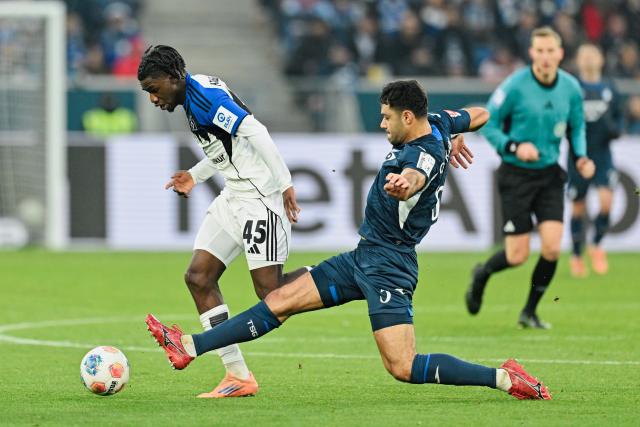 13 December 2025, Baden-Wuerttemberg, Sinsheim: Hamburger's Fabio Balde (L) and Hoffenheim's Ozan Kabak battle for the ball during the German Bundesliga soccer match between TSG 1899 Hoffenheim and Hamburger SV at PreZero Arena. Photo: Uwe Anspach/dpa - WICHTIGER HINWEIS: Gemäß den Vorgaben der DFL Deutsche Fußball Liga bzw. des DFB Deutscher Fußball-Bund ist es untersagt, in dem Stadion und/oder vom Spiel angefertigte Fotoaufnahmen in Form von Sequenzbildern und/oder videoähnlichen Fotostrecken zu verwerten bzw. verwerten zu lassen.