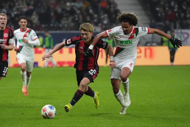 13 December 2025, Hesse, Frankfurt/M.: Augsburg's Han-Noah Massengo (R) and Eintracht Frankfurt's Ritsu Doan battle for the ball during the German Bundesliga soccer match between Eintracht Frankfurt and FC Augsburg at Deutsche Bank Park. Photo: Marc Schüler/dpa - WICHTIGER HINWEIS: Gemäß den Vorgaben der DFL Deutsche Fußball Liga bzw. des DFB Deutscher Fußball-Bund ist es untersagt, in dem Stadion und/oder vom Spiel angefertigte Fotoaufnahmen in Form von Sequenzbildern und/oder videoähnlichen Fotostrecken zu verwerten bzw. verwerten zu lassen.