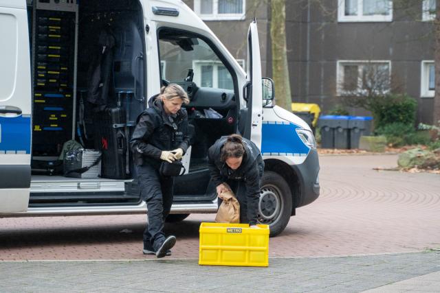 SCREENSHOT - 13 December 2025, North Rhine-Westphalia, Bergkamen: Policewomen stand at a police vehicle for the forensic investigation (KTU) at the scene, where a mother and her four children have been seriously injured in a knife attack in Bergkamen in the Ruhr region. Photo: Max Lametz/dpa