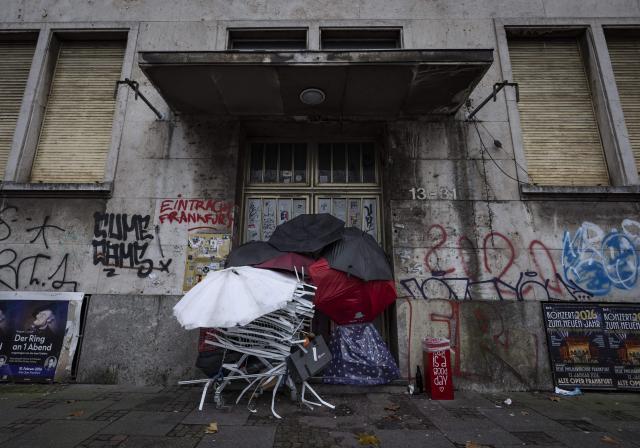 13 December 2025, Hesse, Frankfurt/Main: A homeless man sleeps amongst his personal belongings in an entrance to the former police headquarters. Photo: Boris Roessler/dpa